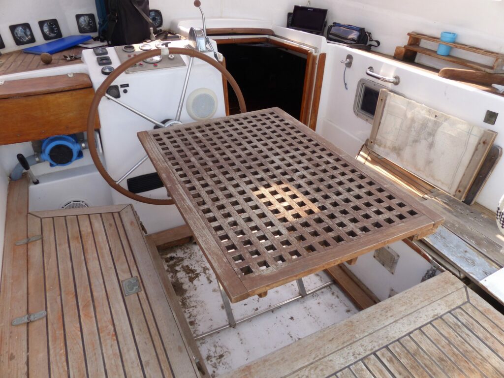 Le cockpit et sa barre à roue, le caillebotis de teck posé à côté de la descente