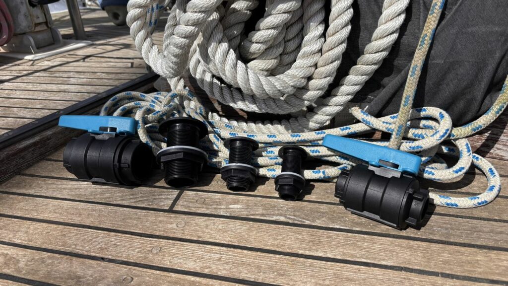 Passe-coques composites et vannes Trudesign neufs, posés sur le pont en teck
